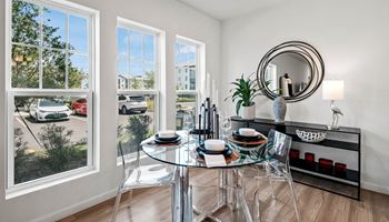 A dining room with a glass table and a large window